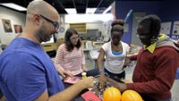 A teacher is working with students on a group project.