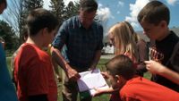 Students and teacher are working together in an outdoor setting.