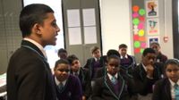 A student is speaking in front of the classroom.