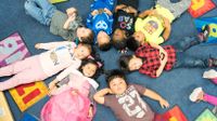 Group of Pre-K kids lying in a circle with their heads touching.
