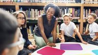 Female teacher engaging with a group of smiling students.