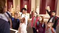 Group of students raising their hands during a museum field trip.