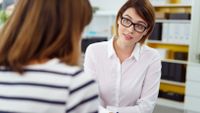 Female teacher engaged in discussion with a parent.