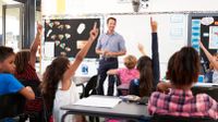 Kids raising hands in an elementary school class.