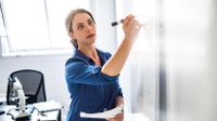 Female teacher writing on whiteboard.