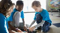 Three elementary students work on a robotics project together