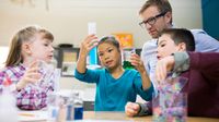 Teacher and elementary students conducting scientific experiment.