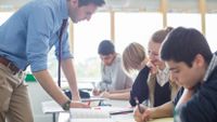 Teacher helping students with a writing assignment in class