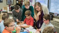 Teacher helping a group of elementary students in the classroom.