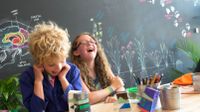 Two students laughing at a table while working on a science project.