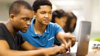Two high school students using a laptop together.