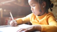 Profile of little girl writing at home.