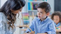 Young schoolboy works with his teacher at school