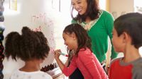 Teacher helping group of students with a math problem