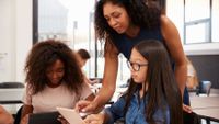 Teacher helping teen students on a tablet