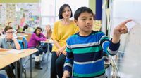 Elementary student pointing at whiteboard in a classroom