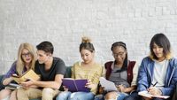 A diverse group of teens reading together on a bench