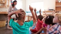 Students raising their hands in a kindergarten class