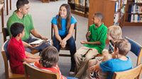 A group of middle school students gathered in chairs in a circle, talking out an issue with an adult