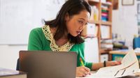 A teacher grading papers in a classroom