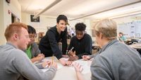 A teacher talking with a group of high school students about their writing projects
