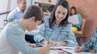 High school students sitting at a table, writing and talking