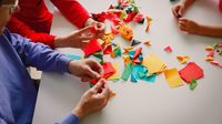 Two children and an adult making origami