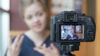 A student filming herself talking on a DSLR camera