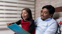 A father reading a picture book with his daughter