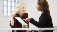 An administrator and a teacher talking at a table, going over a document together