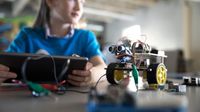 A preteen girl builds a robot in a STEAM lab