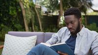 Man reading a book on an outdoor patio