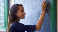 A middle school student doing algebra on a blackboard