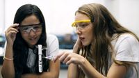 Two students doing a chemistry experiment with a test tube in a school science lab