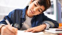 A middle school student writing in a notebook in English class
