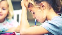 An elementary student working on an assignment, thinking hard