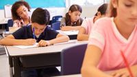 A classroom full of diverse students writing at their desks