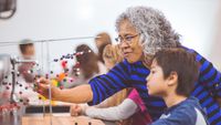 A teacher helping a student with an atom model