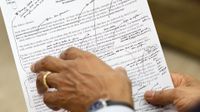 An employee of the Executive Office of the President of the United States is holding President Barack Obama's inaugural address. There are pen marks on it.