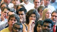 A closeup of a large group of teachers standing shoulder to shoulder in a room. They are all looking in the same direction with a reflective look on their faces.