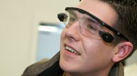 A closeup of a high school boy's face. He's smiling, looking off to the side, wearing tech goggles.