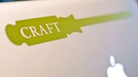 A closeup of the back of a Mac laptop showing the apple icon and a green sticker of a screwdriver that says, "Craft" in white lettering.