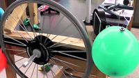 A bicycle wheel and balloon make up part of a Rube Goldberg machine.