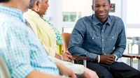 Young man speaking with two adults sitting in semi circle