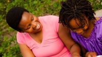Woman and girl sitting close together looking at a binder