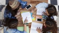 A photo shot from above of four girls working together at a table.