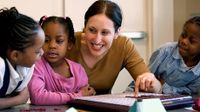 A teacher working with three little kids