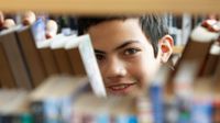Boy looking through books in library stacks