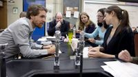 Six adults in the science lab classroom sitting around a table in discussion