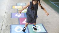 A girl plays hopscotch, unconsciously drawing on natural math capabilities.